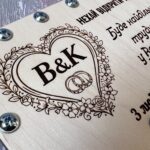 Крупний план гравіювання серця з квітковим візерунком, ініціалами та обручками на дерев'яному конверті