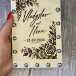 Дерев'яна коробочка з трояндовим візерунком у руці, видно гвинти по периметру