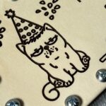Крупний план кота у святковому ковпаку з конфеті на дерев'яній кришці