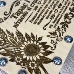Крупний план гравіювання соняшника, качана кукурудзи, голуба та обручок на дерев'яній кришці