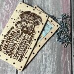 Відкрита дерев'яна коробочка з купюрами всередині та гвинтами з гайками поруч
