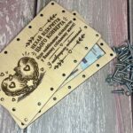 Розкритий дерев'яний конверт із купюрами всередині та гвинтами з гайками поруч